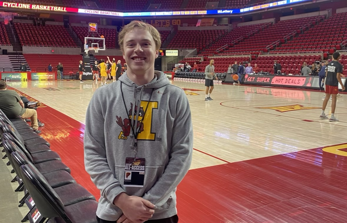 A student poses in front of the ISU men's basketball team at Hilton Coliseum