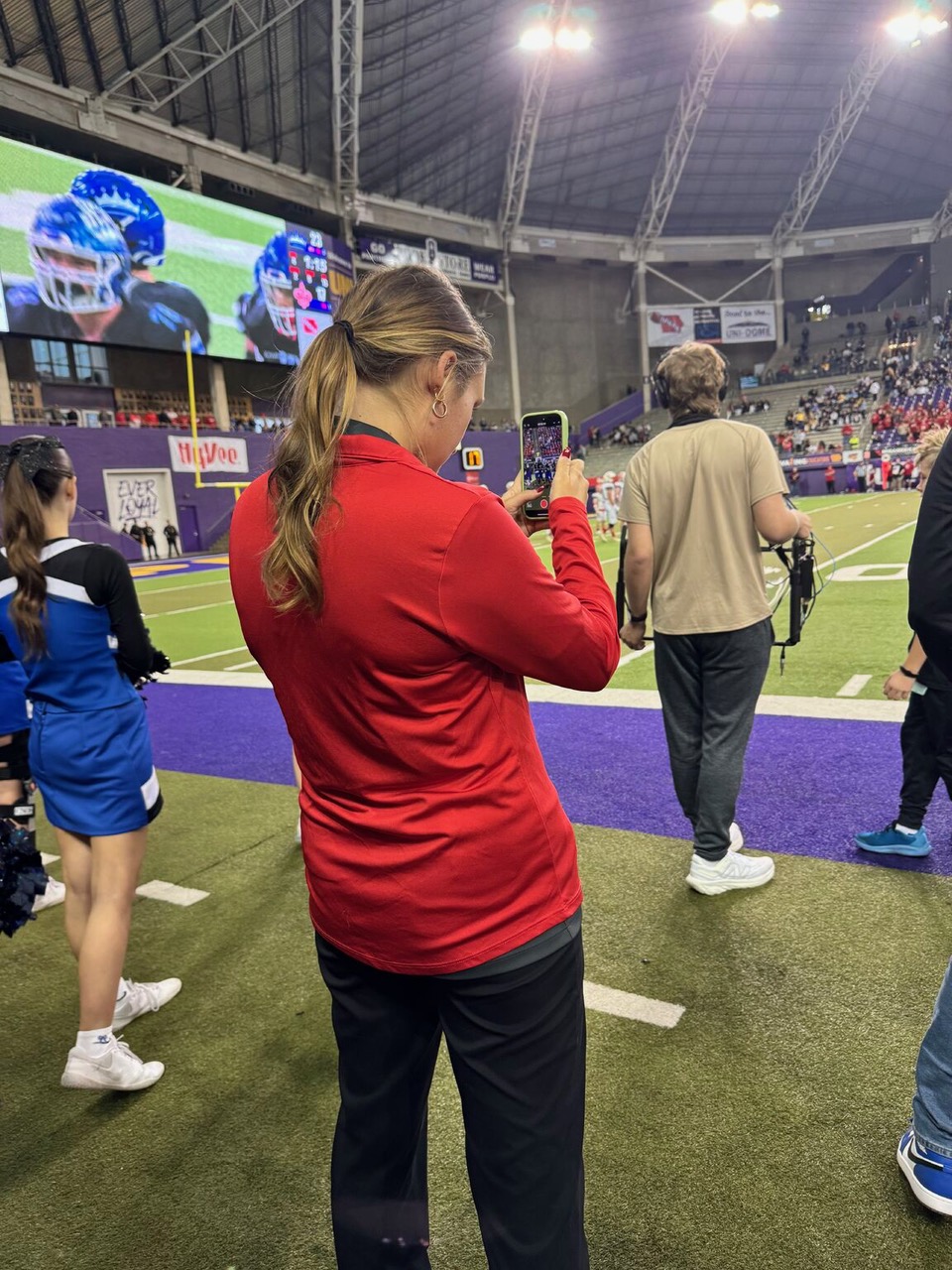 Shae filming a football game on the sidelines